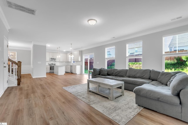 living room featuring light wood-type flooring, visible vents, stairway, and crown molding