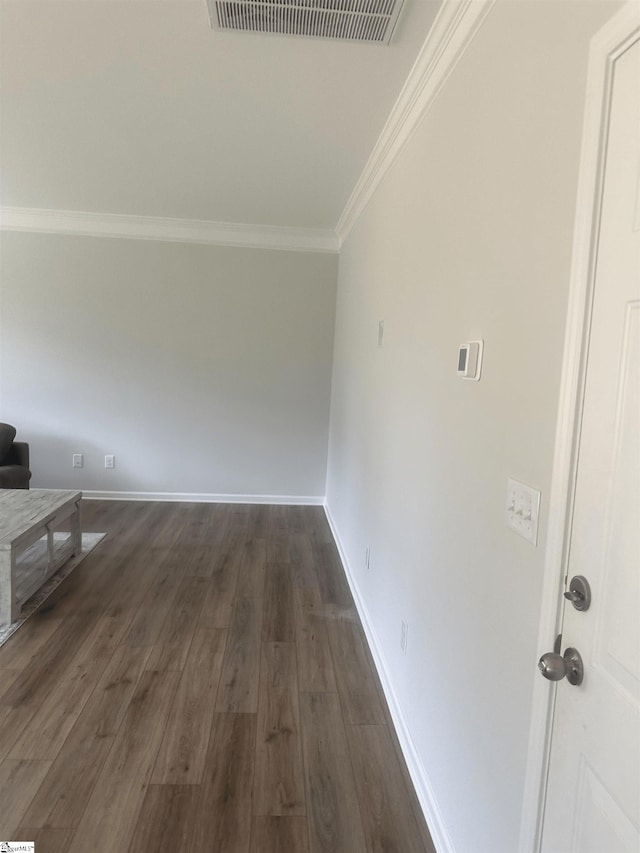 unfurnished living room featuring dark wood-type flooring and ornamental molding