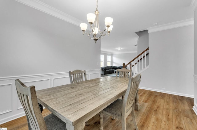 dining area with stairway, crown molding, wainscoting, light wood-style floors, and a notable chandelier