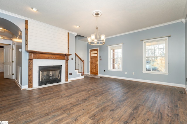 unfurnished living room with a notable chandelier, dark wood-type flooring, a large fireplace, and ornamental molding