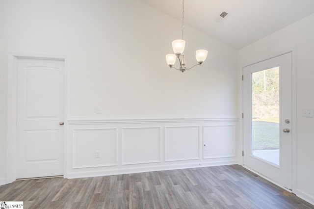 unfurnished dining area with a chandelier, lofted ceiling, and hardwood / wood-style flooring