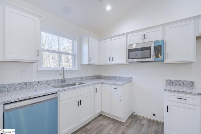 kitchen featuring white cabinetry, sink, light hardwood / wood-style flooring, vaulted ceiling, and appliances with stainless steel finishes