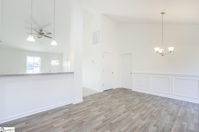 spare room with light hardwood / wood-style flooring, high vaulted ceiling, and ceiling fan with notable chandelier