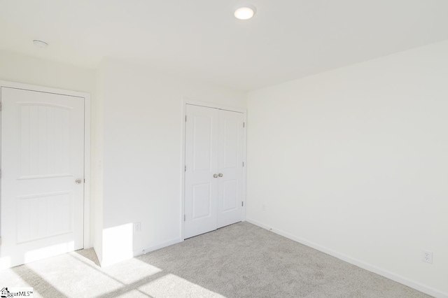 unfurnished bedroom featuring light carpet and a closet