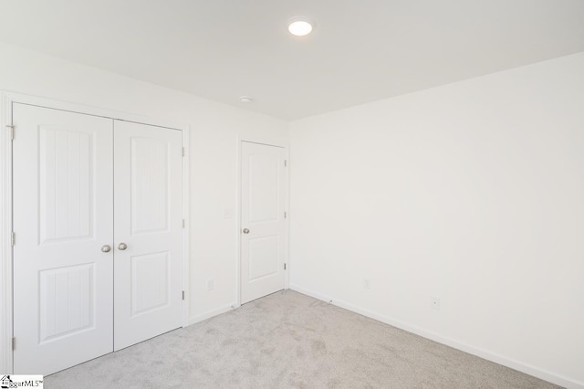 unfurnished bedroom featuring a closet and light colored carpet