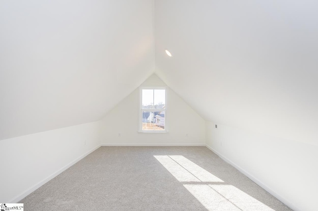 additional living space with light colored carpet and vaulted ceiling