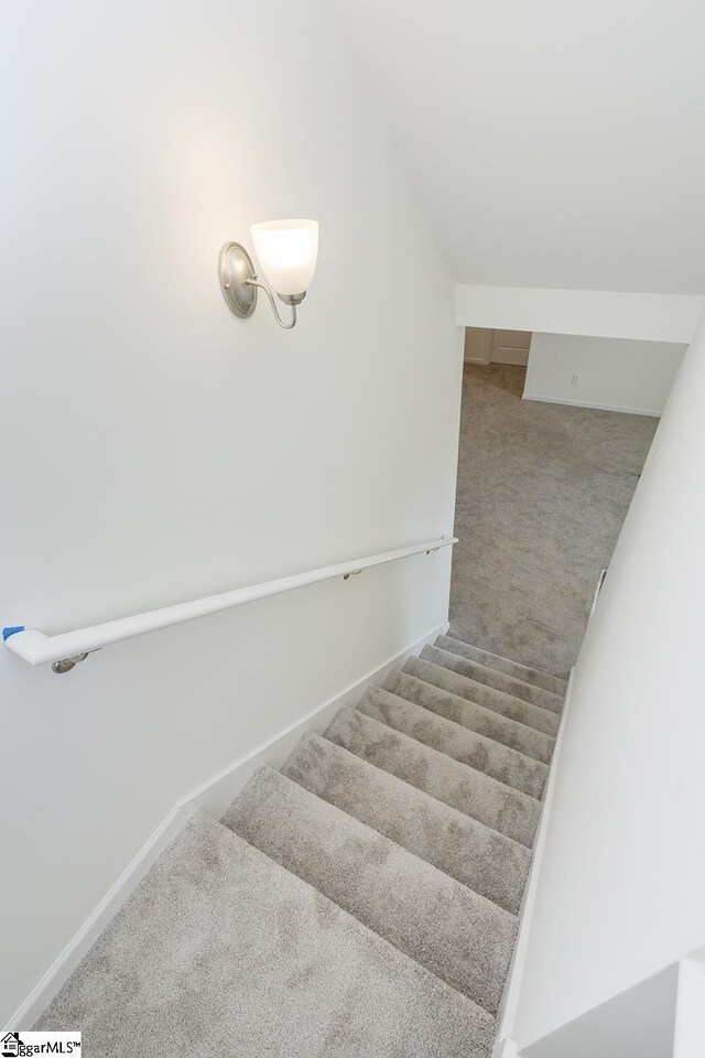 staircase with carpet floors and vaulted ceiling