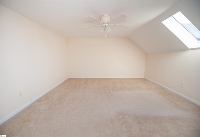 additional living space featuring light colored carpet, vaulted ceiling with skylight, and ceiling fan