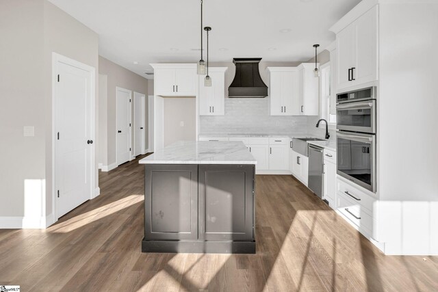 kitchen featuring light stone countertops, appliances with stainless steel finishes, sink, a kitchen island, and white cabinets