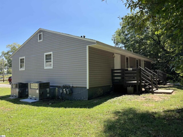 view of side of property featuring central AC and a lawn