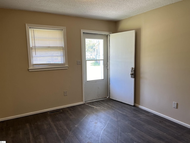 doorway to outside featuring visible vents, dark wood finished floors, a textured ceiling, and baseboards