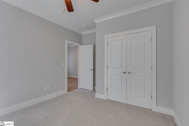 unfurnished bedroom featuring light colored carpet, a closet, crown molding, and ceiling fan