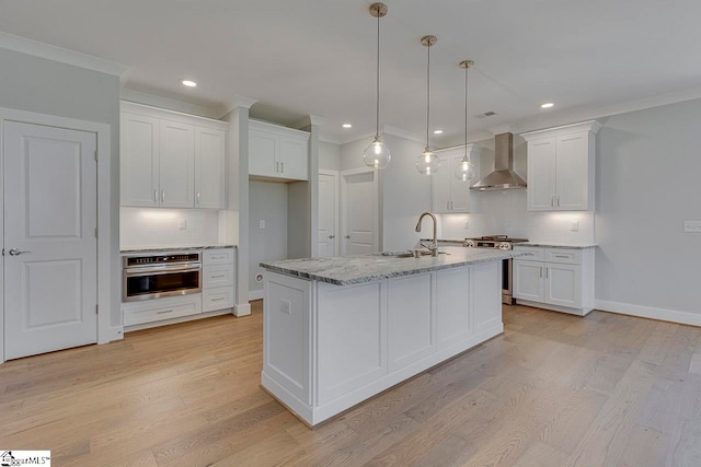 kitchen featuring stainless steel appliances, light hardwood / wood-style floors, wall chimney range hood, and white cabinetry