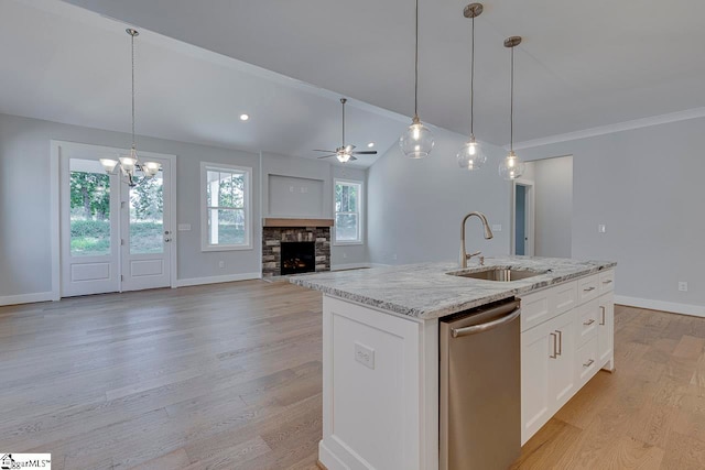 kitchen featuring light hardwood / wood-style floors, stainless steel dishwasher, ceiling fan with notable chandelier, and a fireplace