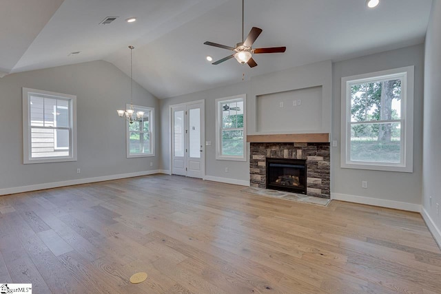 unfurnished living room featuring light hardwood / wood-style floors, ceiling fan with notable chandelier, a stone fireplace, and lofted ceiling