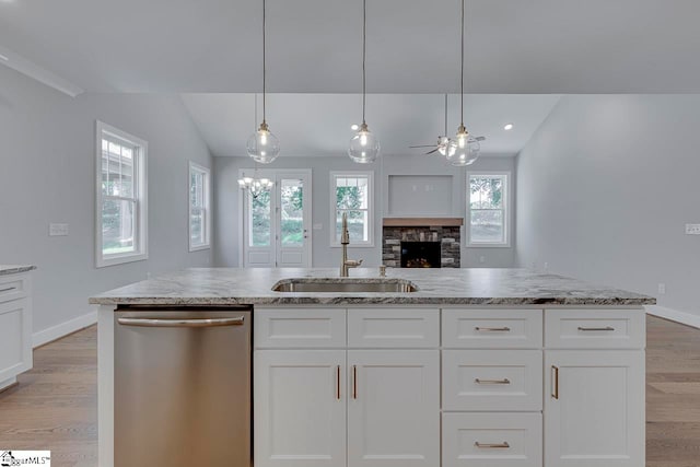 kitchen with light hardwood / wood-style flooring, a stone fireplace, dishwasher, sink, and lofted ceiling