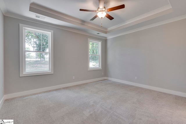 carpeted empty room featuring ceiling fan, crown molding, and a tray ceiling