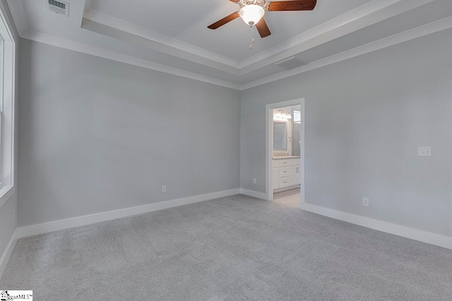 carpeted empty room featuring ceiling fan, a raised ceiling, and crown molding