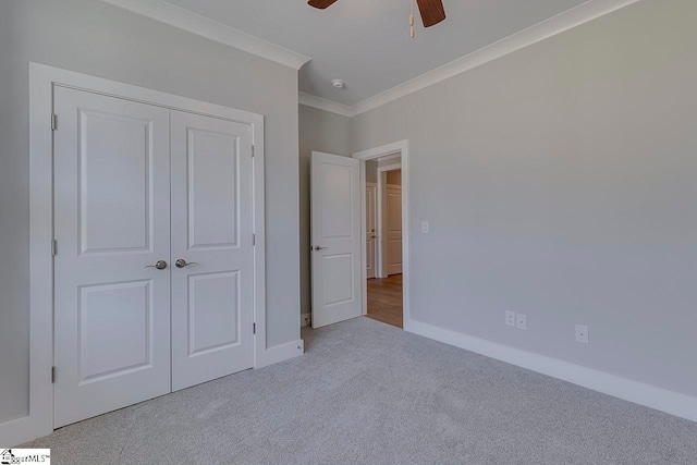 unfurnished bedroom with ceiling fan, a closet, carpet floors, and crown molding