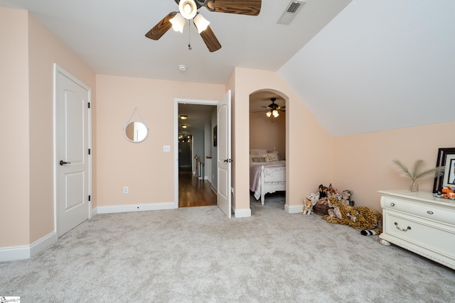 interior space featuring ceiling fan, vaulted ceiling, connected bathroom, and light colored carpet