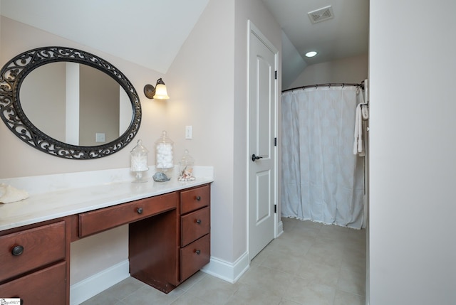 bathroom with tile patterned flooring, lofted ceiling, vanity, and walk in shower