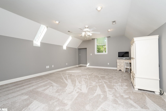 additional living space with ceiling fan, vaulted ceiling with skylight, and light colored carpet