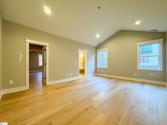 spare room featuring light wood-type flooring, lofted ceiling, and baseboards