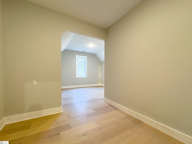 bonus room featuring lofted ceiling, baseboards, and light wood-style floors