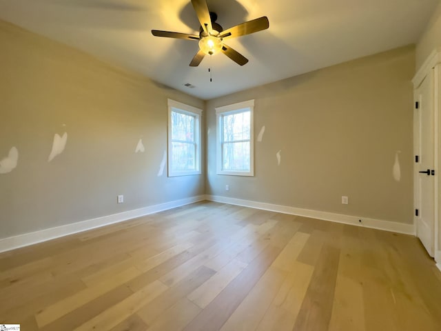 spare room with visible vents, ceiling fan, light wood-style flooring, and baseboards