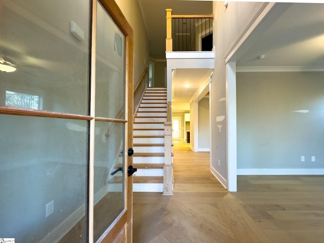 staircase featuring ornamental molding, parquet flooring, and baseboards