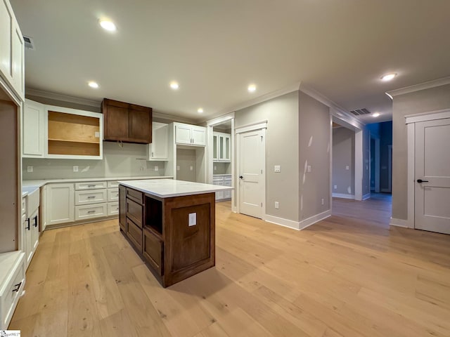 kitchen featuring a center island, open shelves, light countertops, visible vents, and light wood-style floors