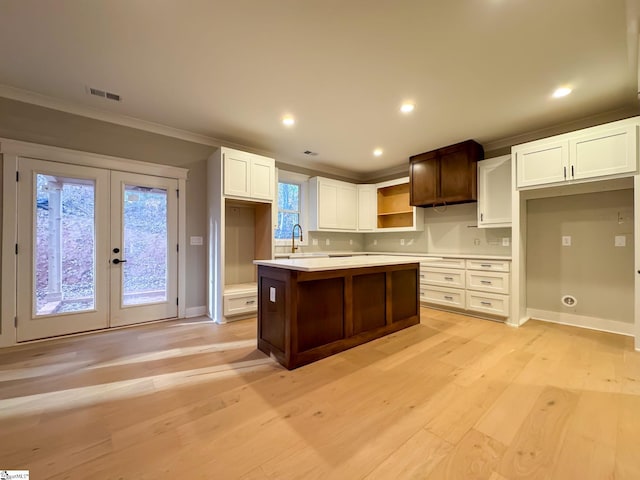 kitchen with visible vents, a kitchen island, light countertops, light wood-style floors, and open shelves