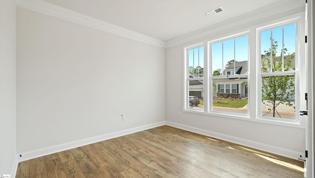 unfurnished room with baseboards, crown molding, and hardwood / wood-style flooring