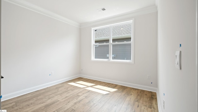 spare room with crown molding, light wood finished floors, and baseboards