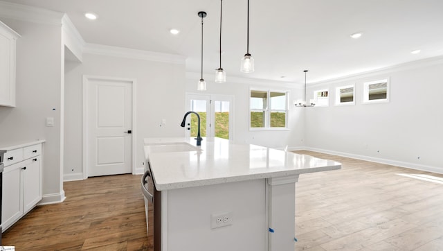 kitchen featuring a sink, ornamental molding, light wood-style floors, white cabinetry, and baseboards