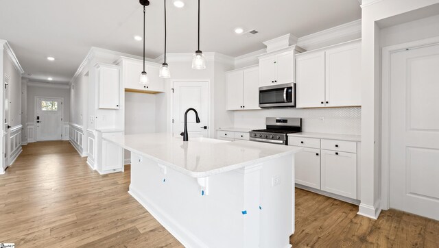 kitchen featuring appliances with stainless steel finishes, a sink, ornamental molding, recessed lighting, and light wood-style floors