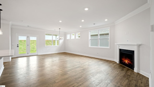 unfurnished living room with ornamental molding, a lit fireplace, dark wood-type flooring, a chandelier, and baseboards