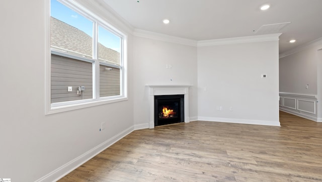 unfurnished living room with crown molding, a warm lit fireplace, wood finished floors, recessed lighting, and baseboards