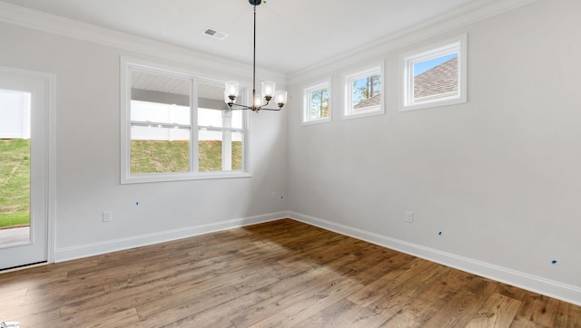 unfurnished dining area featuring ornamental molding, a chandelier, baseboards, and wood finished floors