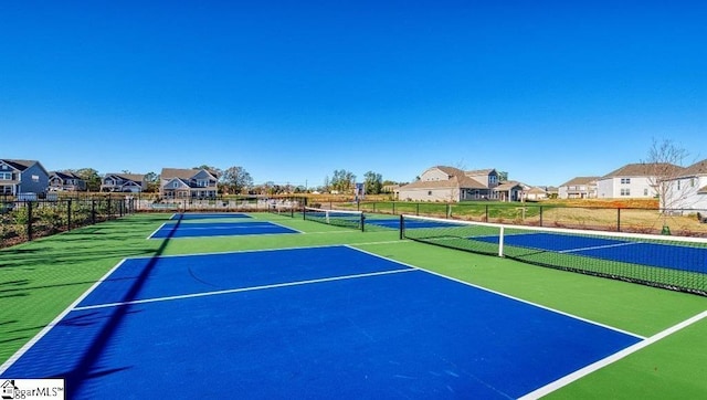 view of tennis court with a residential view and fence