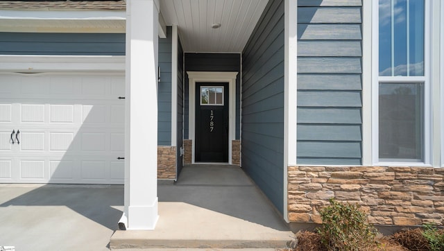 entrance to property with stone siding and an attached garage