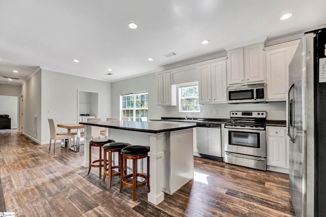 kitchen with visible vents, dark countertops, appliances with stainless steel finishes, dark wood-type flooring, and a center island