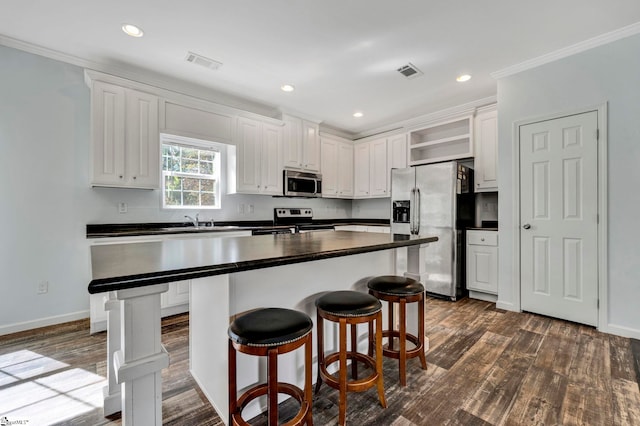 kitchen featuring visible vents, dark countertops, appliances with stainless steel finishes, white cabinetry, and open shelves