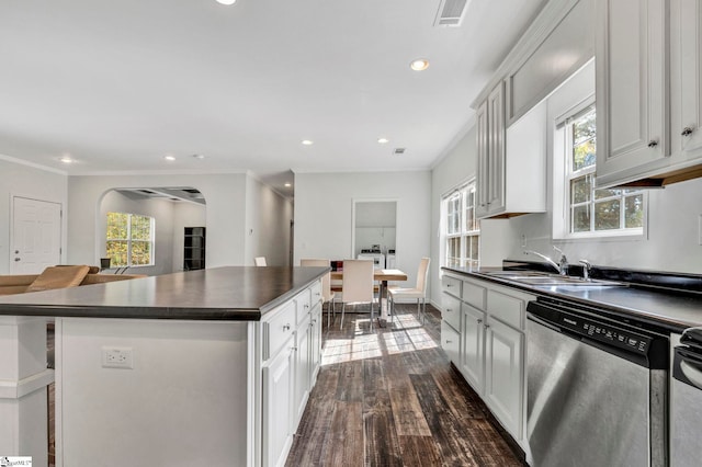 kitchen featuring visible vents, arched walkways, dishwasher, dark countertops, and a sink