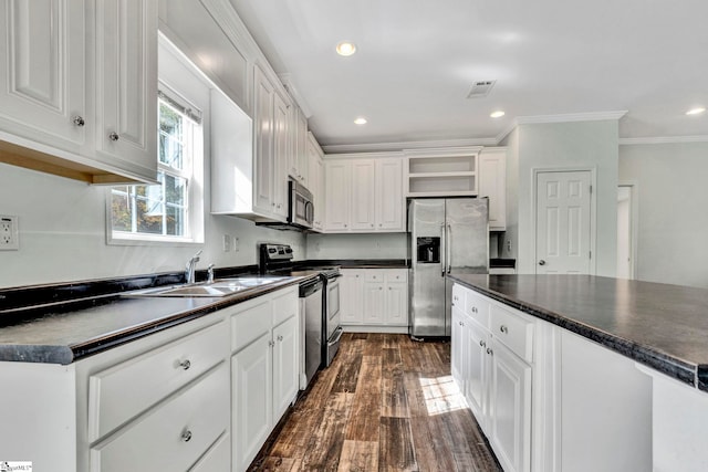 kitchen featuring white cabinets, dark countertops, stainless steel appliances, open shelves, and a sink