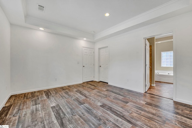 unfurnished room with ornamental molding, a raised ceiling, visible vents, and wood finished floors