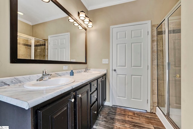 full bath with wood finished floors, a stall shower, a sink, and crown molding