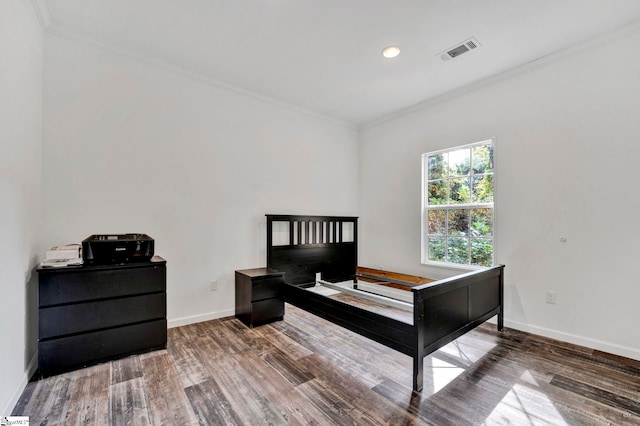 bedroom with baseboards, visible vents, wood finished floors, and ornamental molding