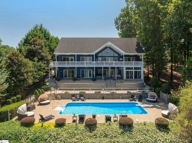 back of house with a balcony, a fenced in pool, and a patio