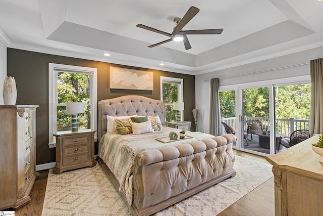 bedroom featuring ceiling fan, crown molding, light hardwood / wood-style flooring, and a tray ceiling